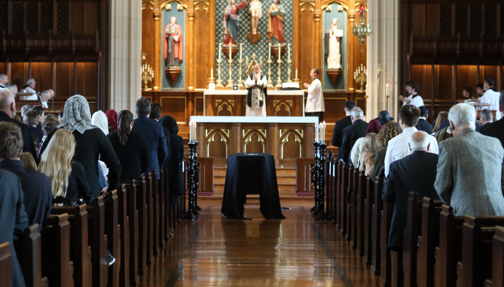 Fr. Markey begins the funeral Mass. In the foreground, the casket in the aisle