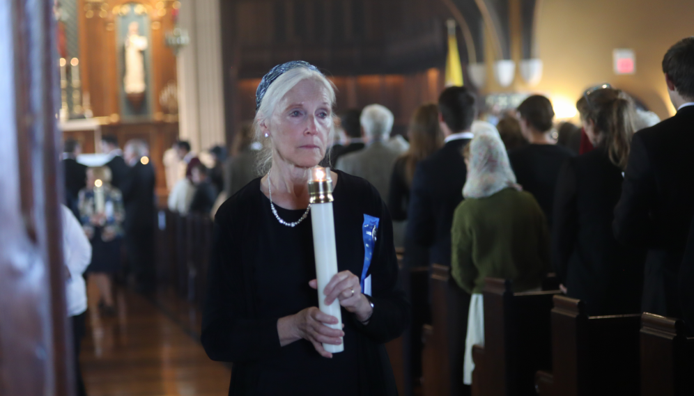 A friend of Nurse Nancy's processes out, mournful, candle in hand