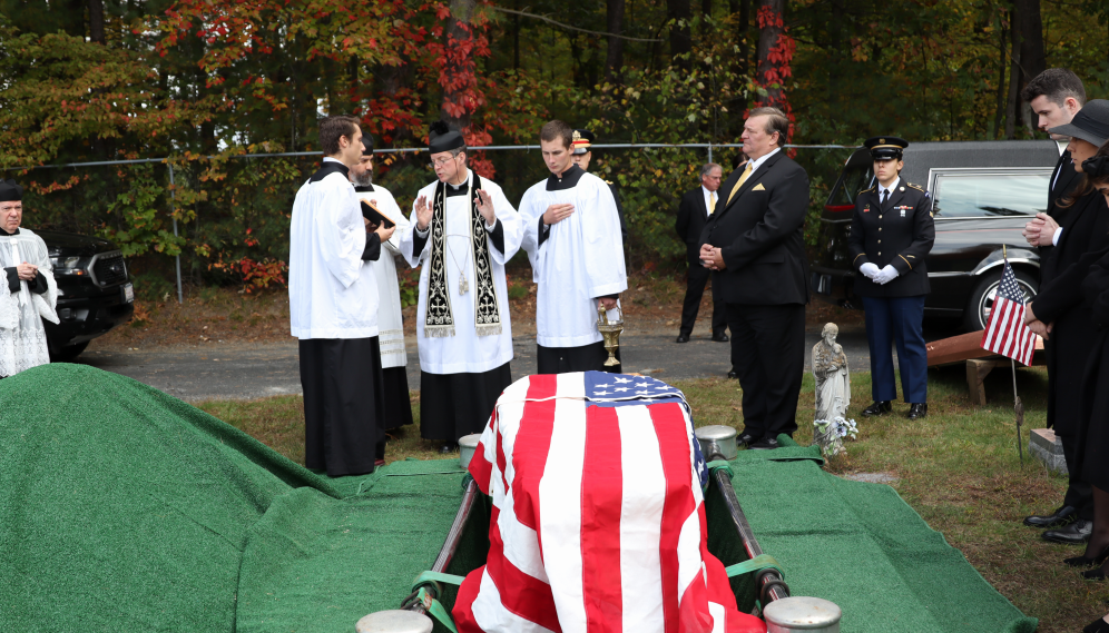 Fr. Markey blesses the casket before it is lowered into the grave