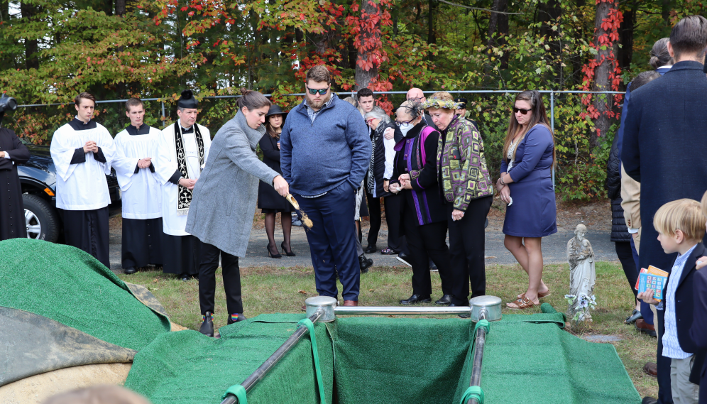 People throw down scoops of earth on the lowered casket