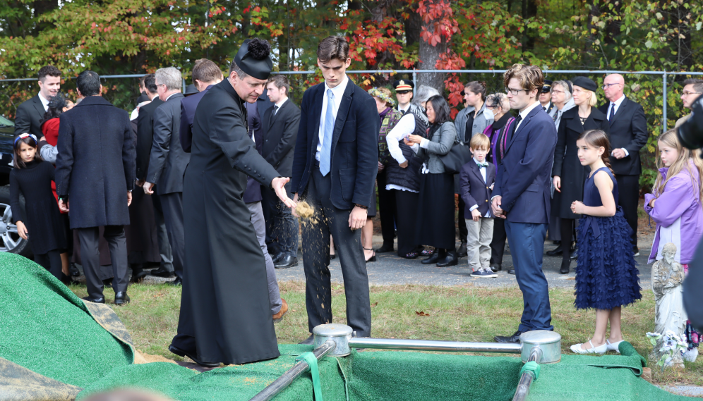 Fr. Markey casts a handful of earth into the grave