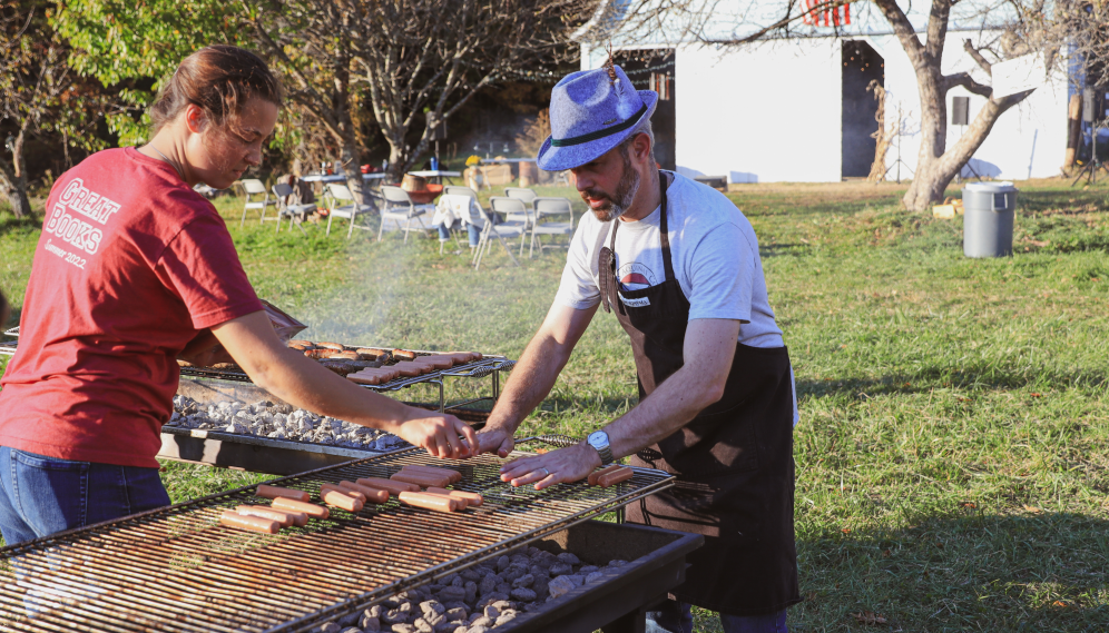 A fedora-wearing Dr. Gardner assists with grilling the hot dogs