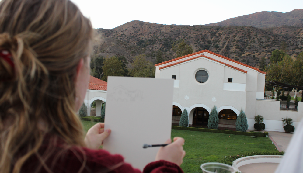 A student compares her sketch of St. Albert Hall to the actual building