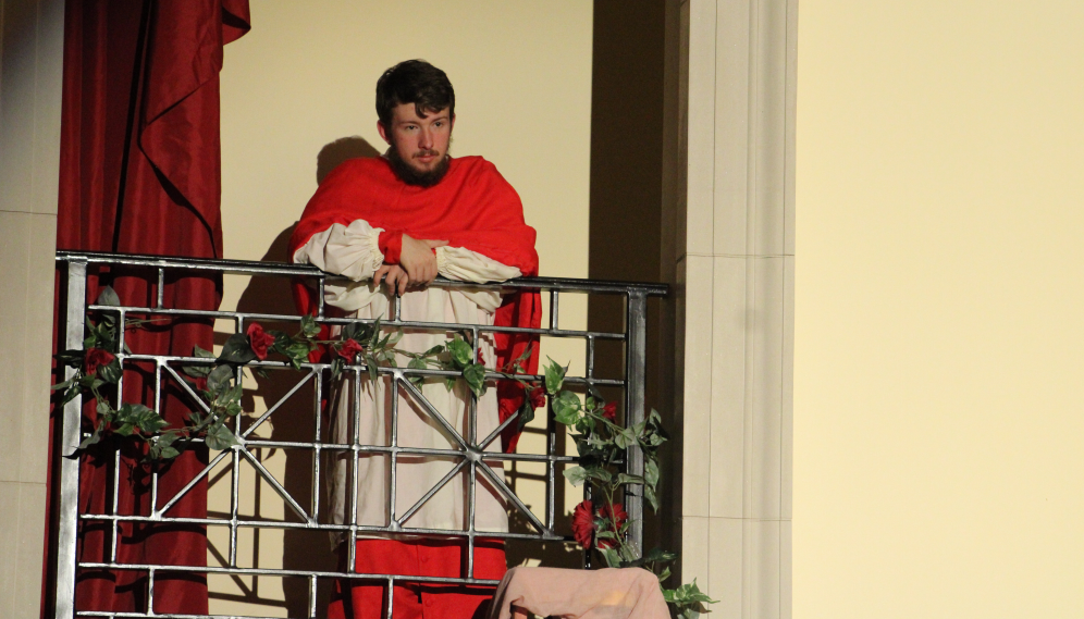 A character looks down from a balcony