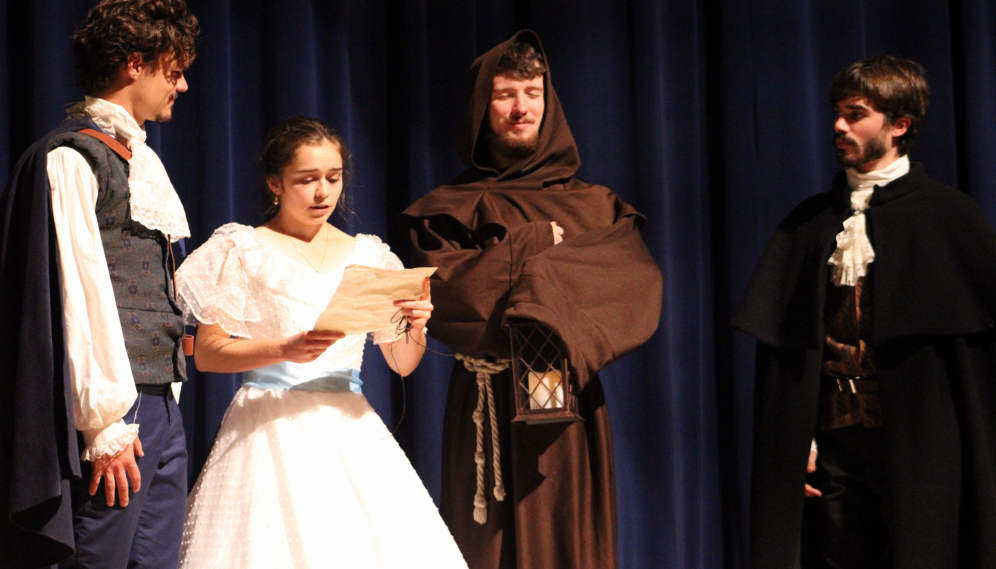 One character reads a letter before three onlookers