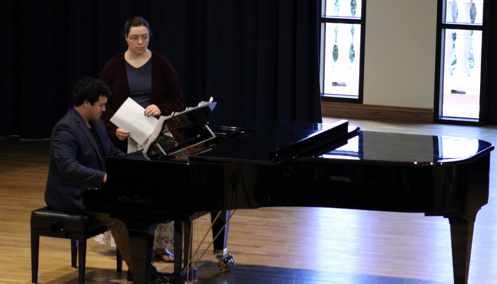 A pianist performs while another turns the pages