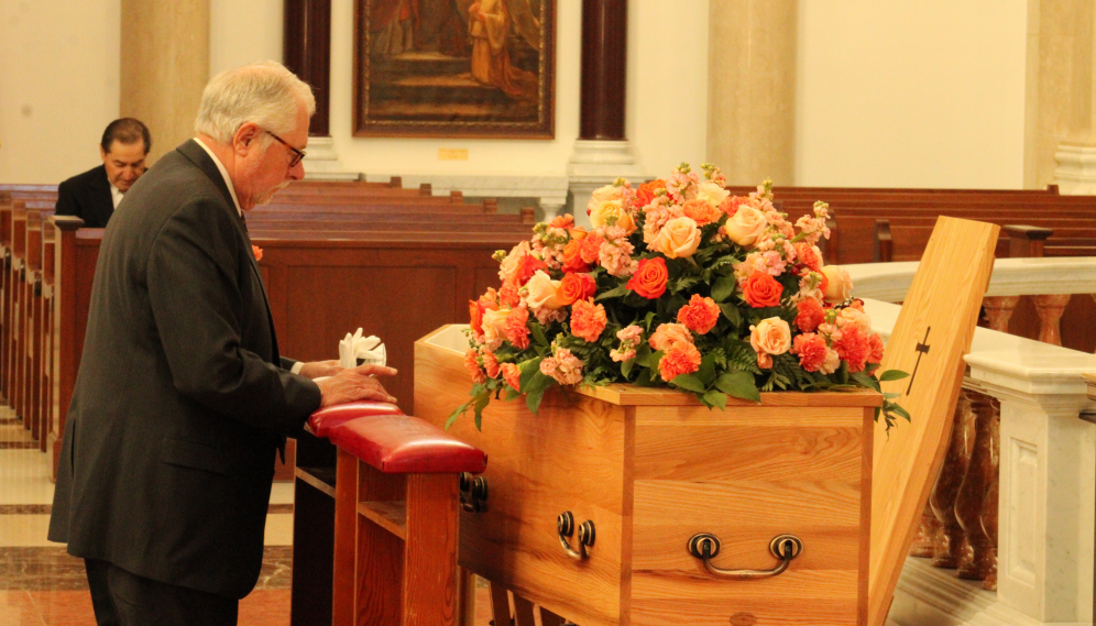 Dr. McLean kneels before the open casket