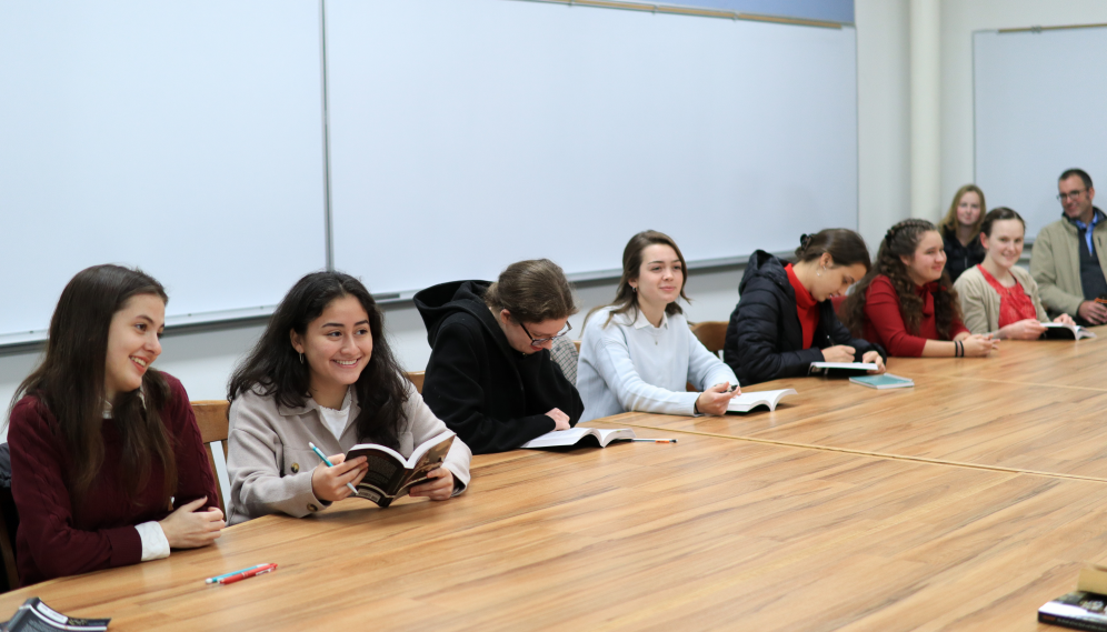 The students smile and laugh on one side of the seminar table