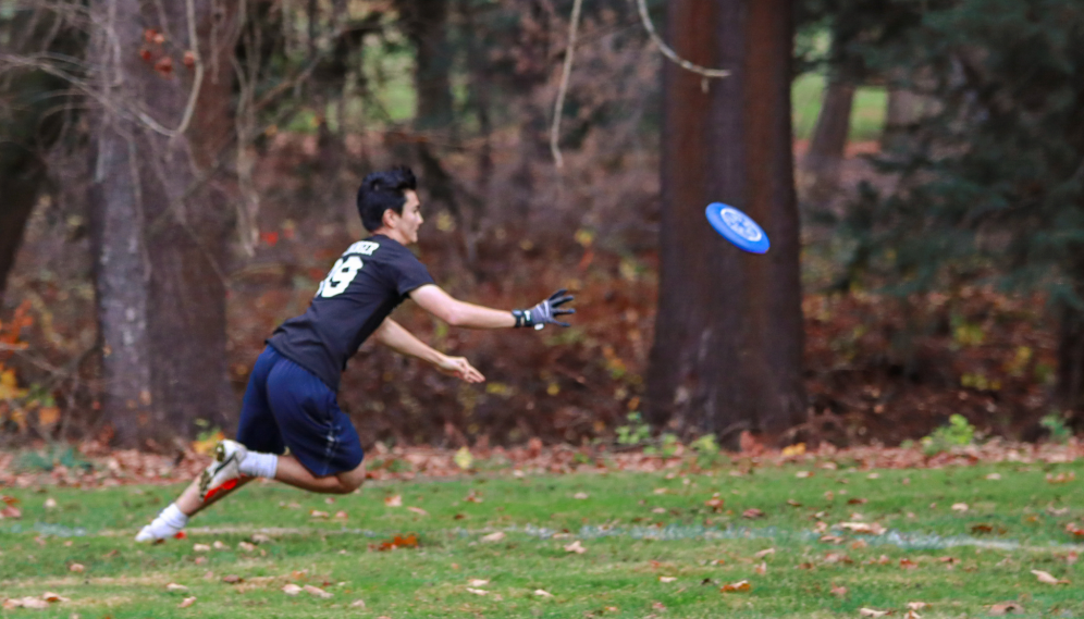 A TMC student runs full tilt to catch a difficult pass