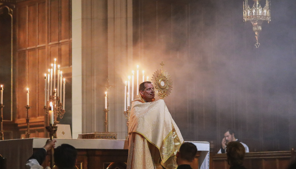 Fr. Markey raises Our Lord in the monstrance amid clouds of incense