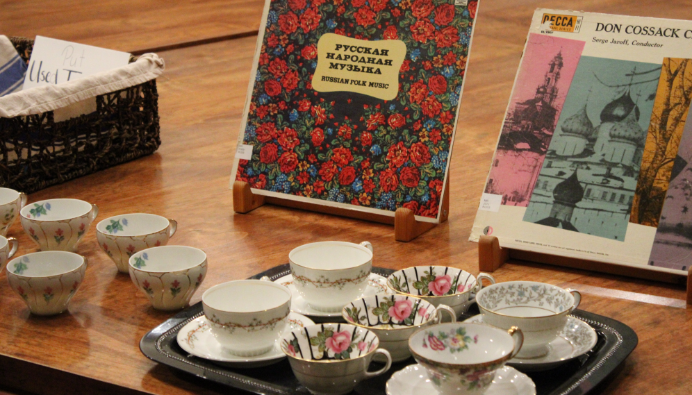 A tray of teacups laid out before the covers of two records of Russian music