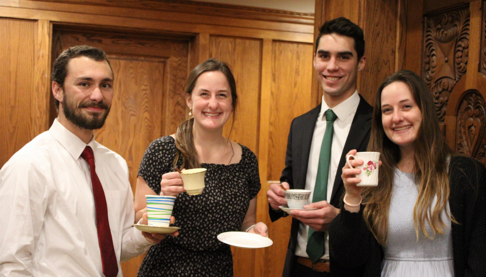 Four smile for the camera, teacups in hand