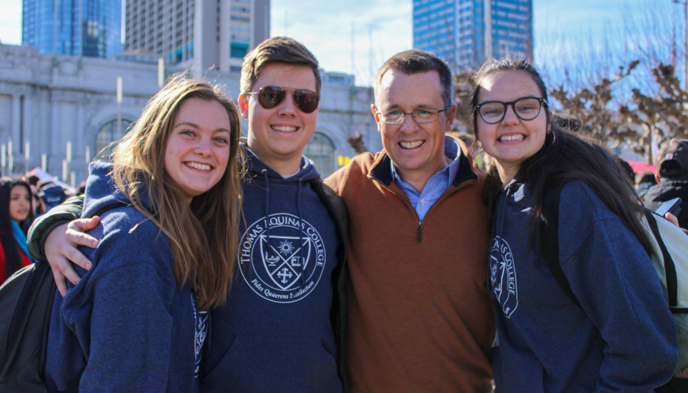 Jon Daly poses for a photo with three students