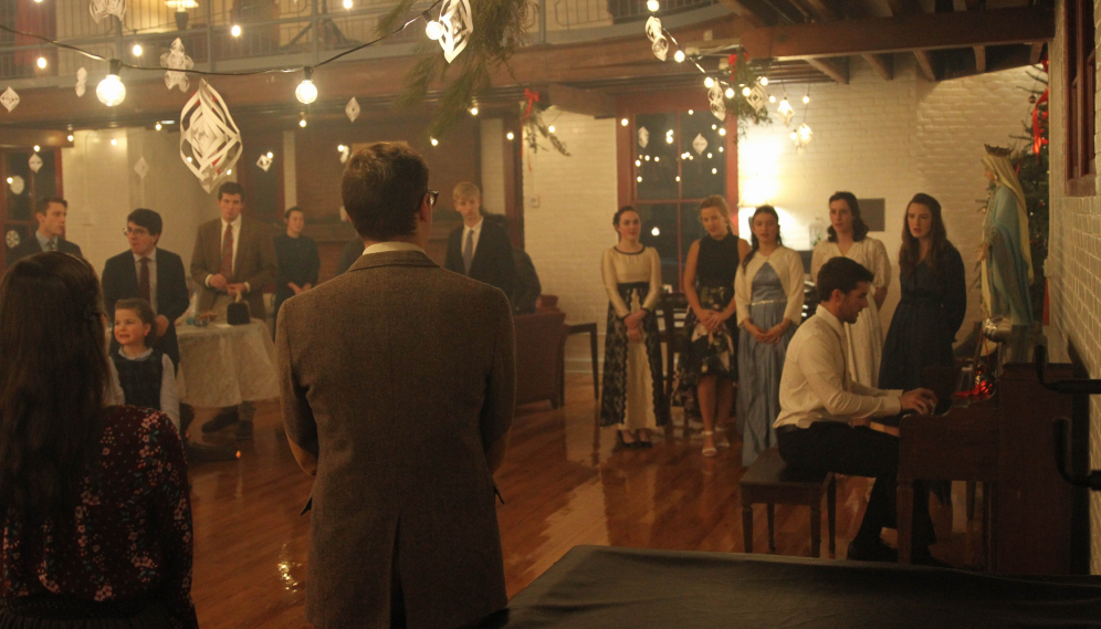 Students sing carols as one accompanies on the piano