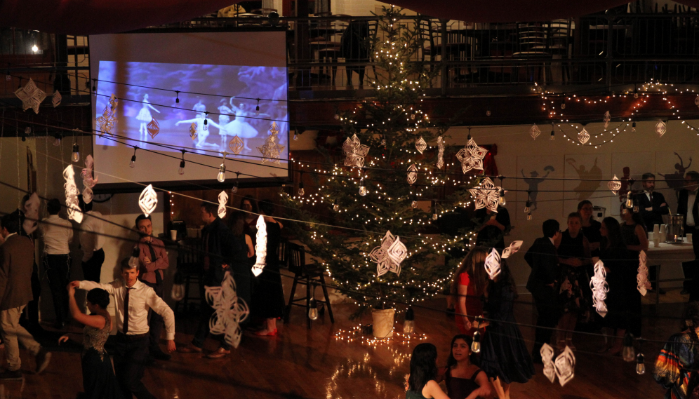 A view from above, with couples dancing, lights twinkling, a Christmas tree, and Nutcracker playing on a screen in the background