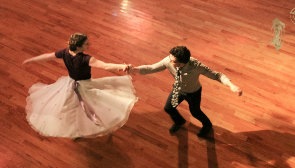 Overhead view: As two dance, the girl's skirt flares as she performs a quick turn