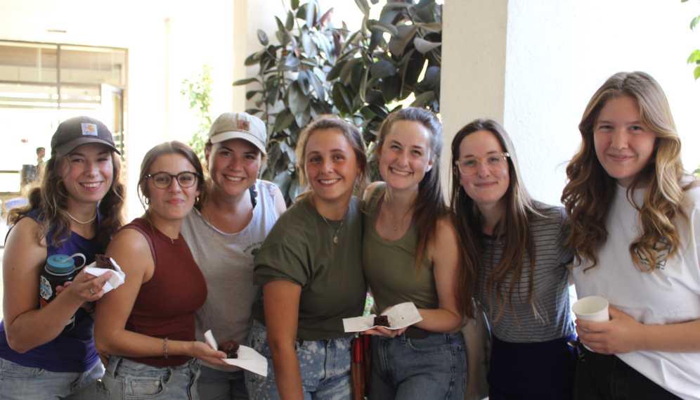Seven pose for a photo, banana bread in hand
