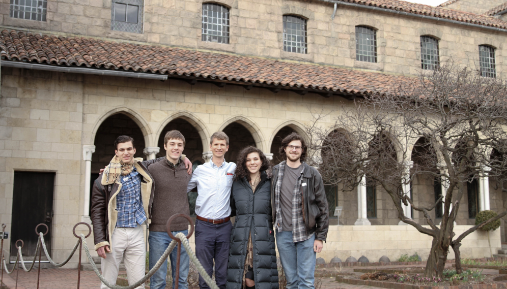 Five pose in front of a row of arches