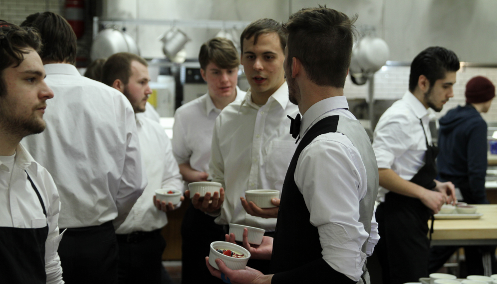 In the kitchen, servers line up to go out with the desserts