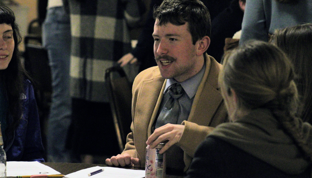 Students chat, seated at a Commons table