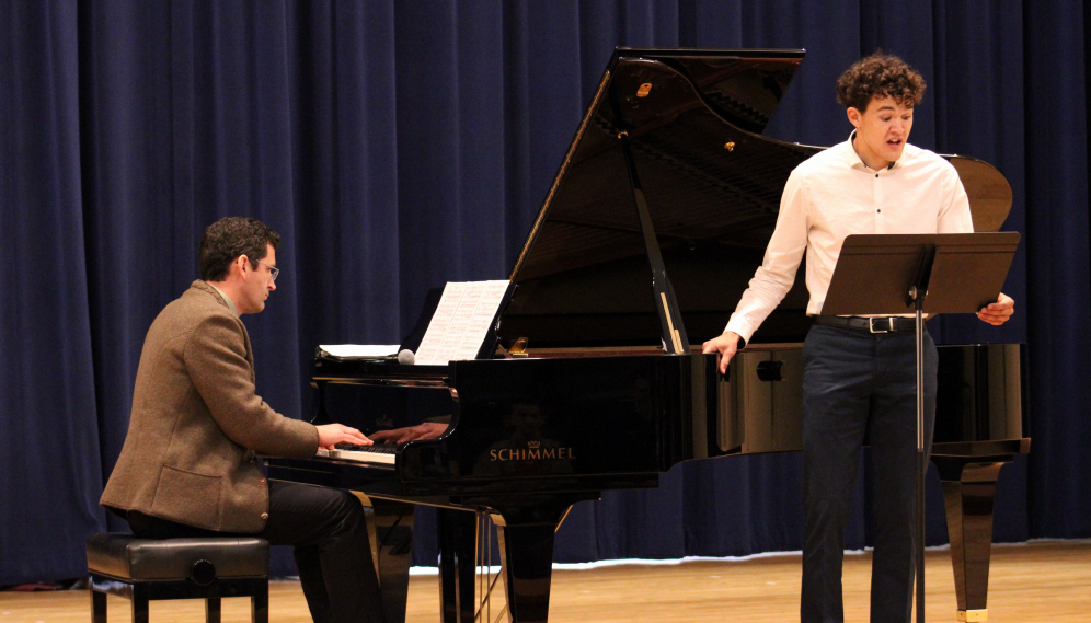 One sings while another accompanies on piano