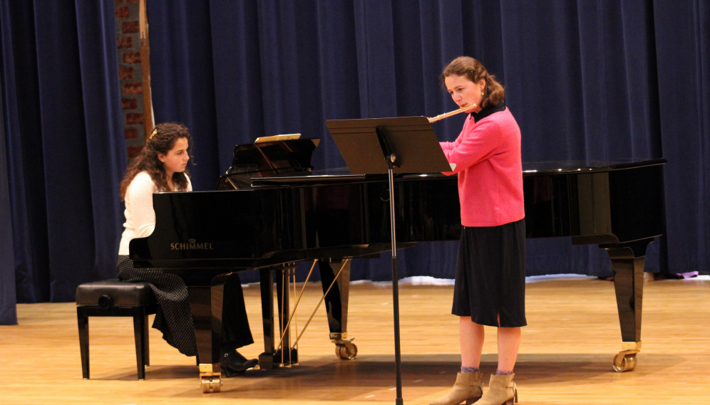 One plays piano while another plays flute