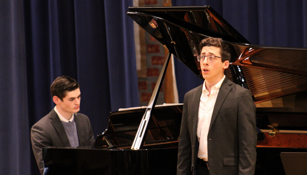 One sings while another accompanies on piano