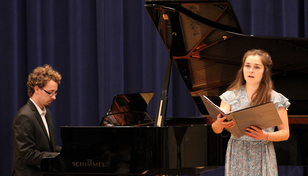 One sings while another accompanies on piano