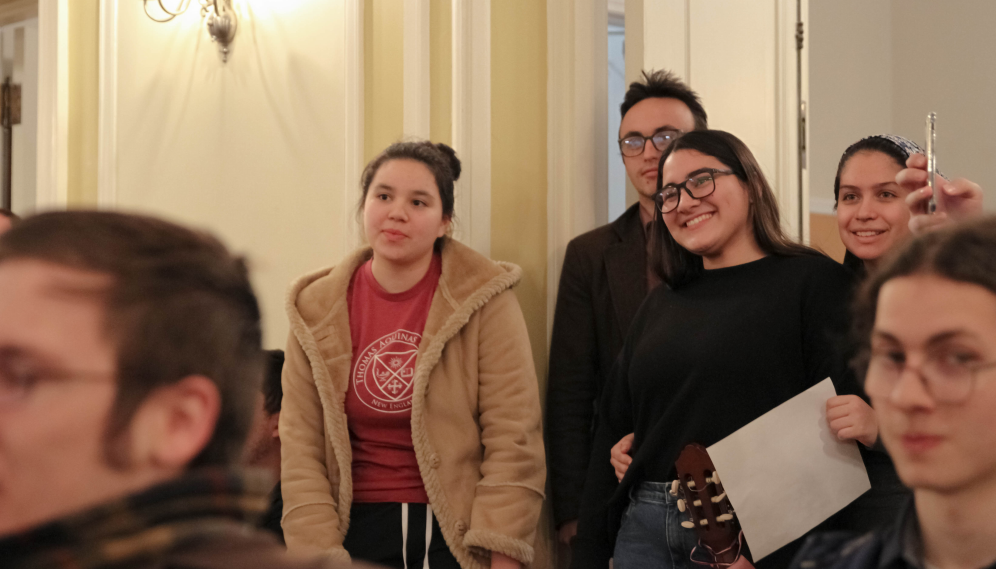 Students watch, standing in the back