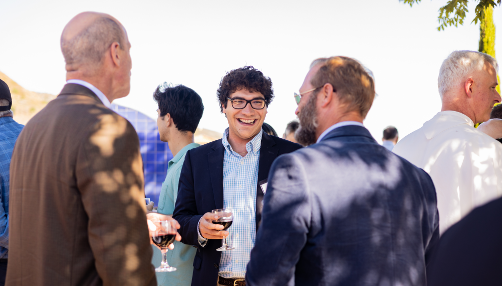 Three laugh and chat together over wine