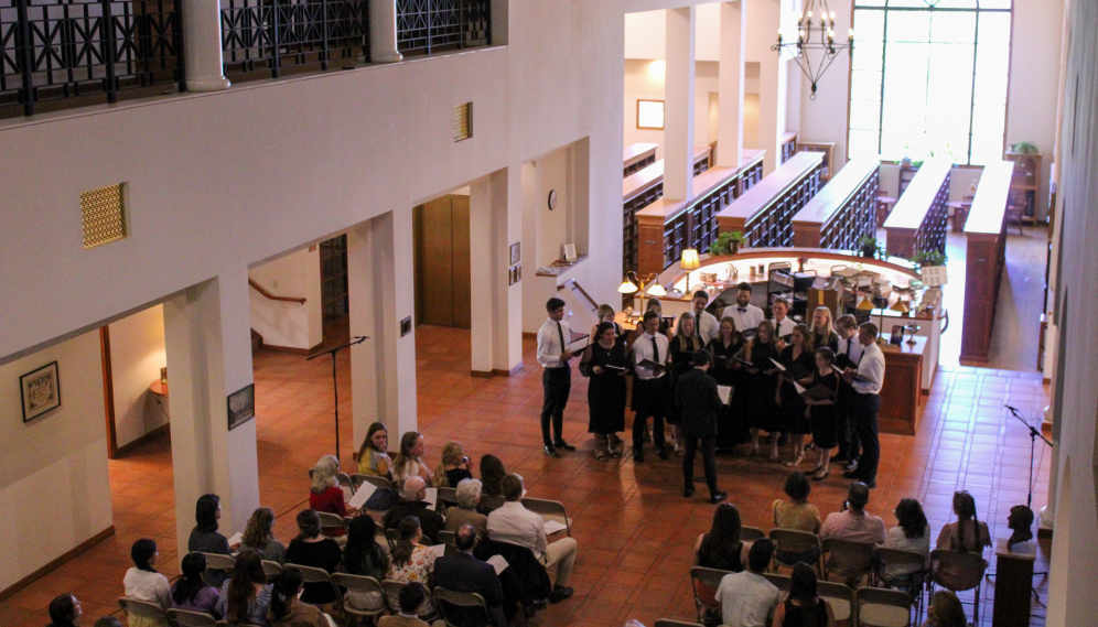 Chrystomos performs in the library afront the circ desk