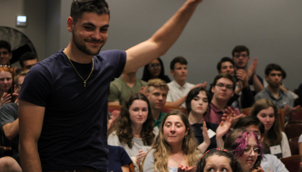 A prefect waves to the students as he is introduced