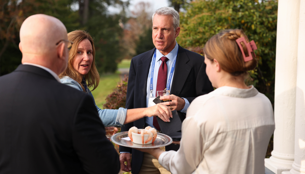 Friends of the college talk over a shrimp cocktail