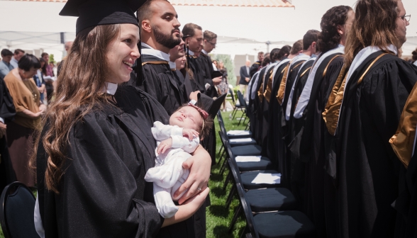 Married graduates hold their sleeping baby