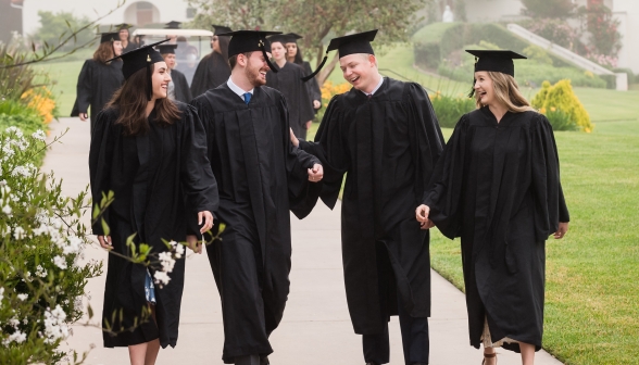 Newly-minted graduates walk down the path, chatting together