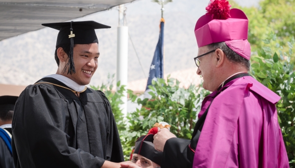 A graduate receives his diploma from a bishop