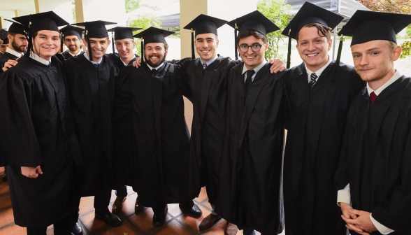 Graduates interlock arms and pose for a photo