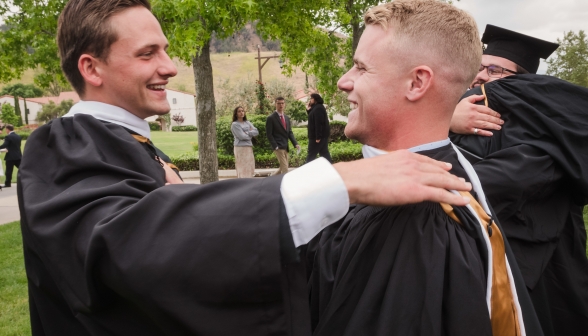 Joyful grads hug one another