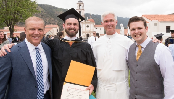 Two graduates pose, one with his Father and one with Fr. Walsh