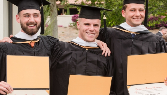 Happy graduates pose with their diplomas