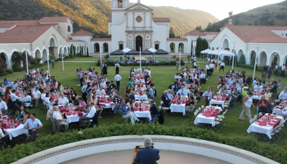 Long shot of alumni seated with chapel in background