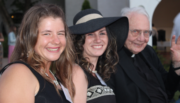 Members of recently-graduates classes pose for a photo with Fr. Buckley