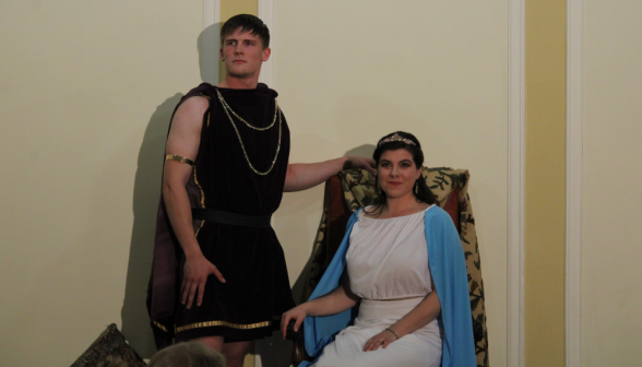 Dido is seated on her throne. Aeneas stands beside her.