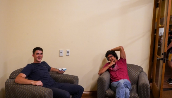 Two students lounging in a pair of armchairs