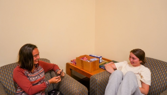 Two girls chat in a pair of armchairs in a corner