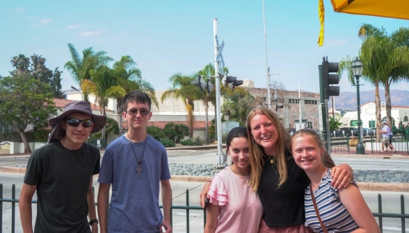 Five students smile for the camera afront a railroad crossing 