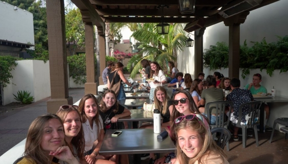 Students fill the outdoor tables of a little sidewalk cafe