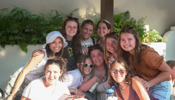 Ten girls pose afront a planter box with ferns