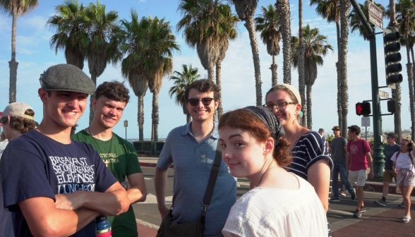 A little group of students turns from conversation to smile at the camera