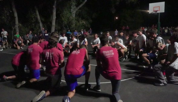 The men students kneel in prayer before their game